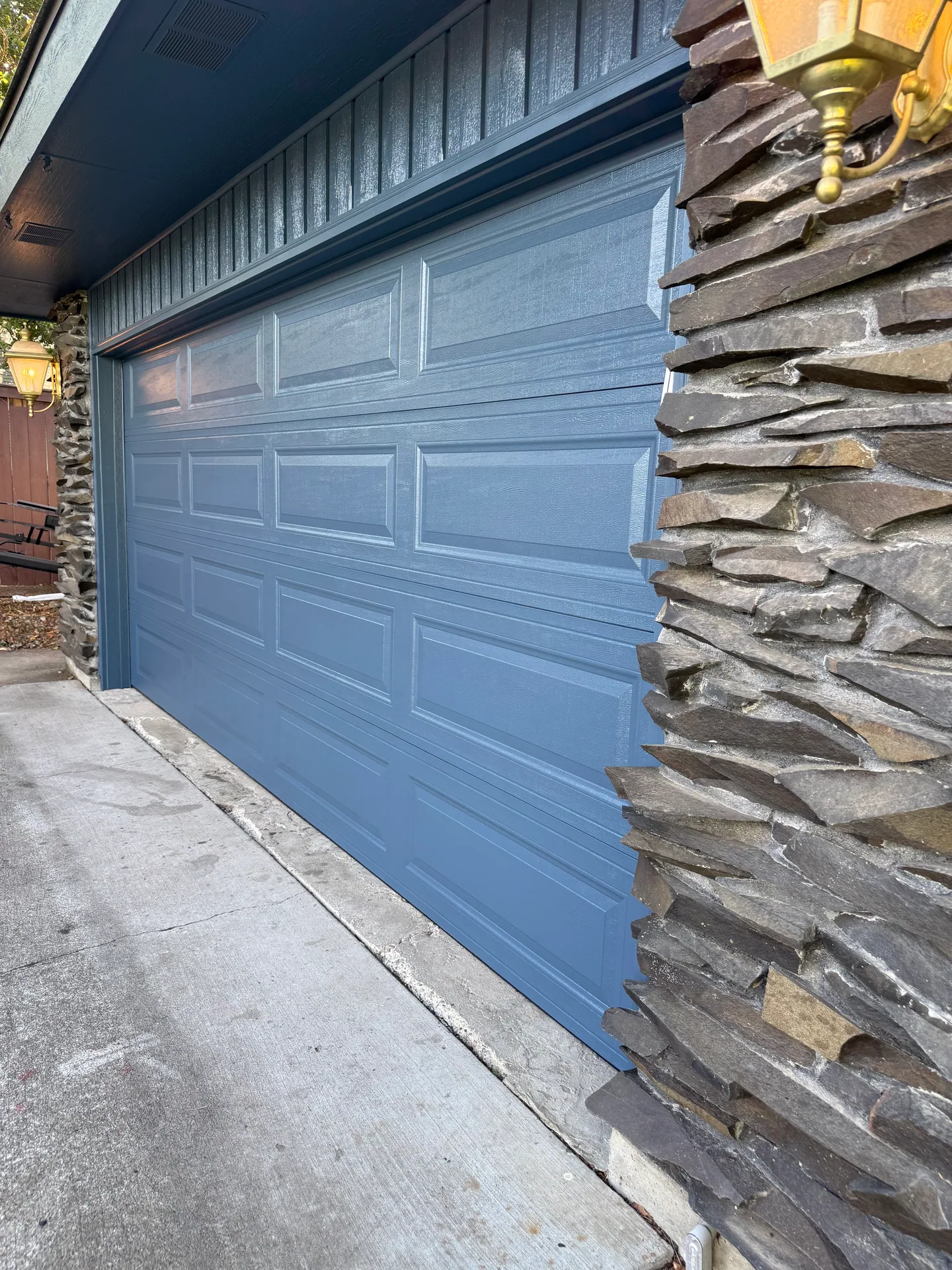 Blue garage door and freshly painted siding beside stonework